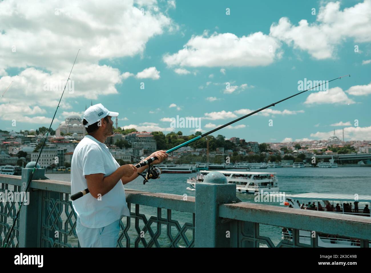Pêcheur sur le pont Eminönü Galata, grand angle, temps nuageux, homme d'âge moyen en blanc, couleur rustique, concept de tourisme, passe-temps et loisirs Banque D'Images