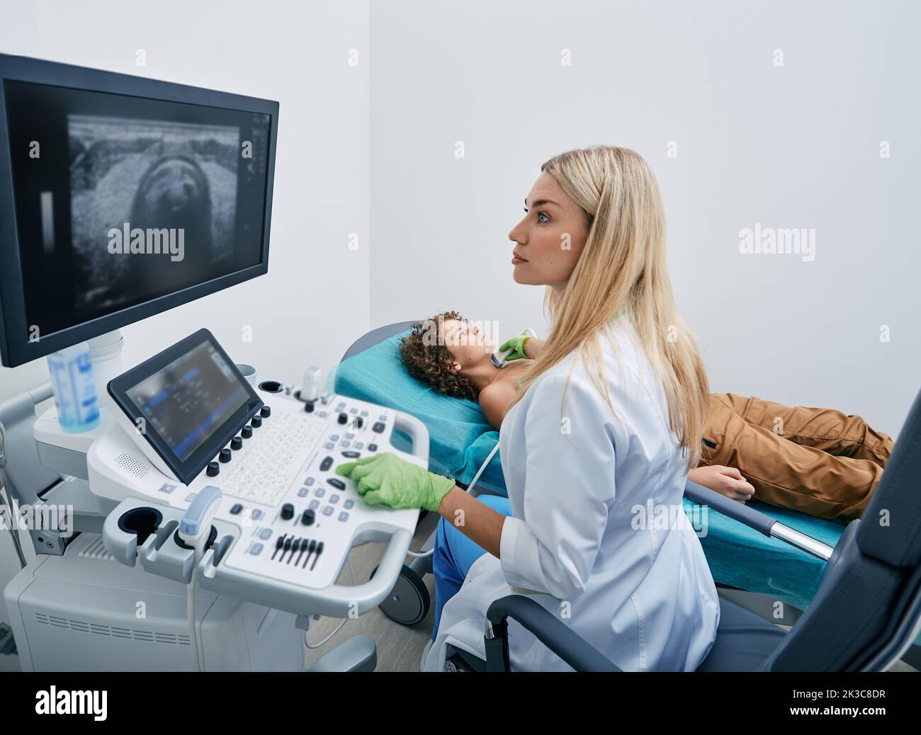 médecin faisant l'échographie à l'enfant patient masculin au bureau d'échographie de la clinique médicale. Diagnostic échographique de la thyroïde chez l'enfant Banque D'Images