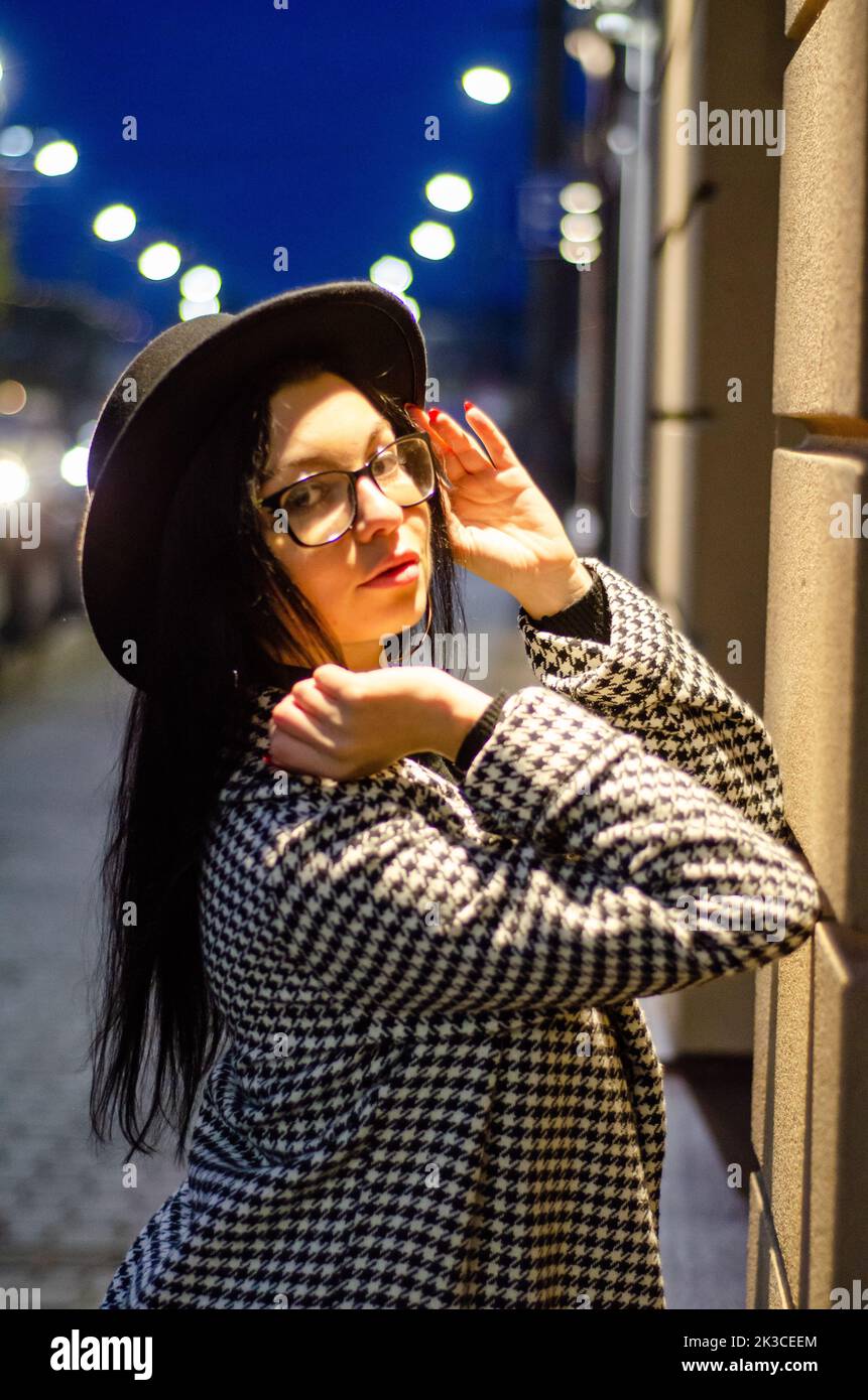 Portrait d'une fille dans un chapeau marchant dans la ville de nuit Banque D'Images