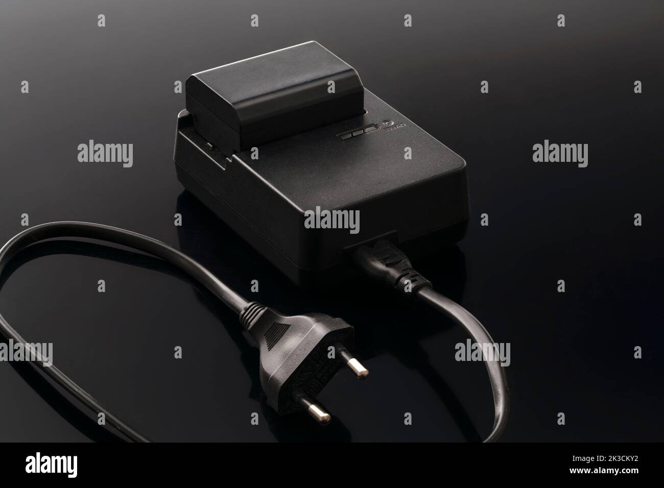 le chargeur et la batterie de l'appareil photo et des appareils ménagers sont noirs sur fond sombre. Banque D'Images