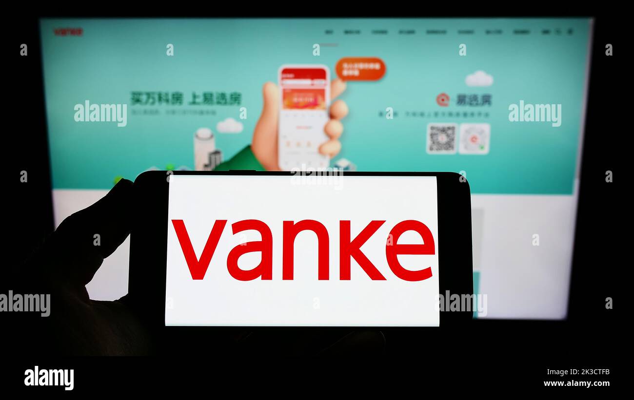 Personne tenant un smartphone avec le logo de la société immobilière chinoise Vanke Co. Ltd. À l'écran devant le site Web. Mise au point sur l'affichage du téléphone. Banque D'Images