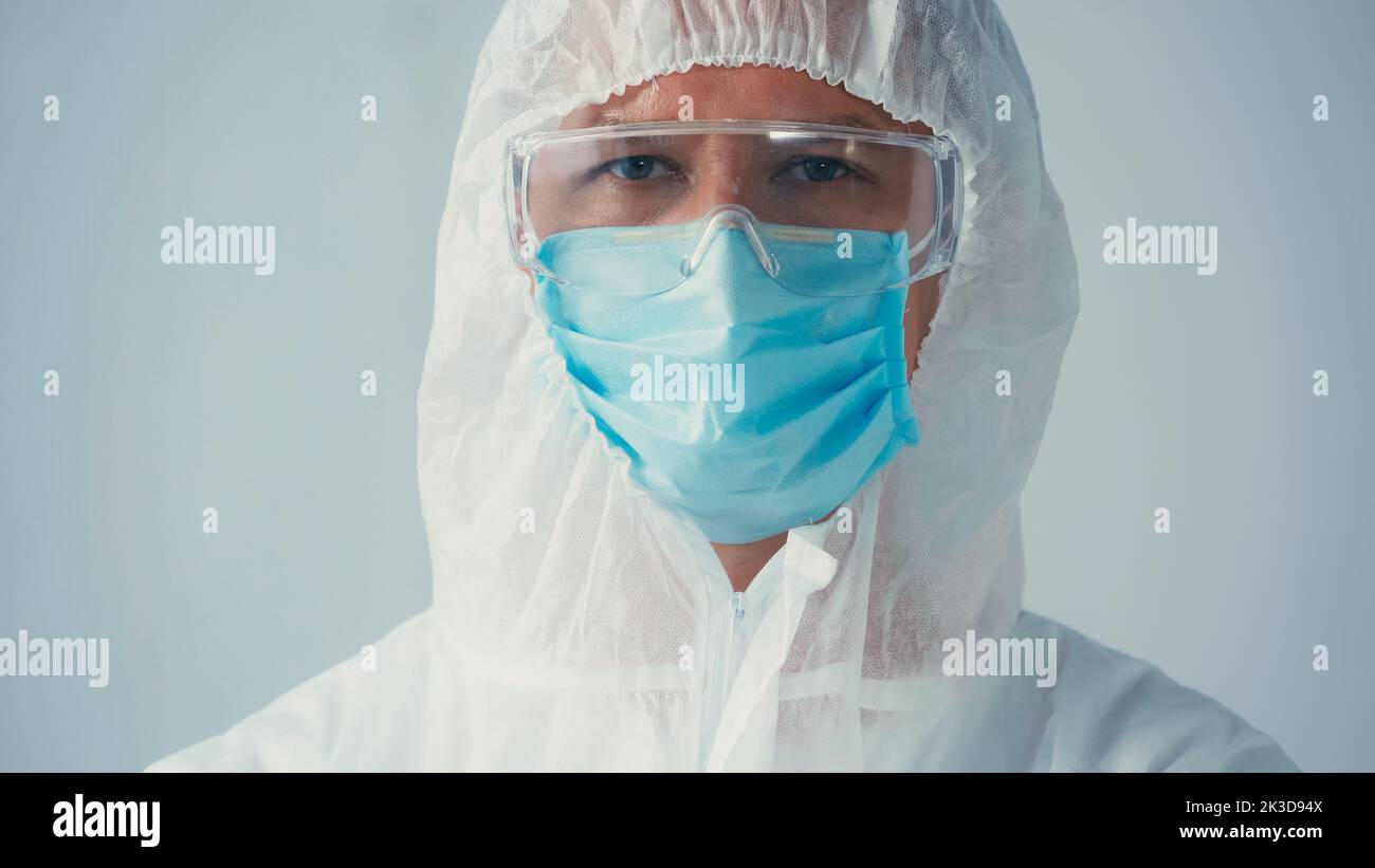 portrait de scientifique en costume de noisette et lunettes de protection avec masque médical regardant la caméra isolée sur gris, image de stock Banque D'Images
