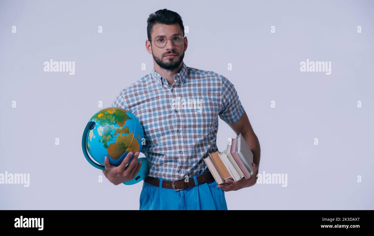 étudiant nerd avec globe et pile de livres regardant la caméra isolée sur gris, image de stock Banque D'Images