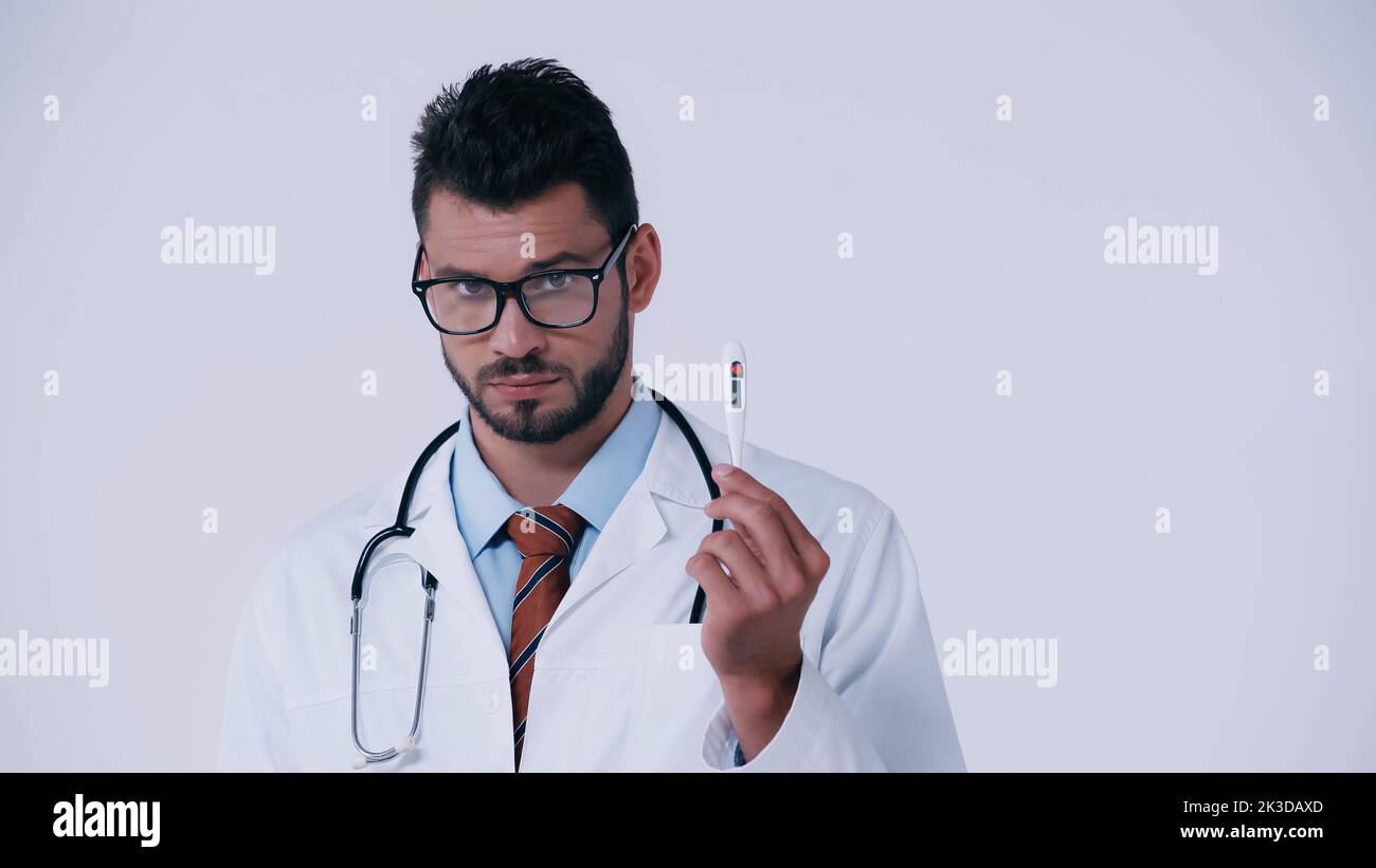 brunette médecin en lunettes montrant thermomètre électronique isolé sur image grise Banque D'Images