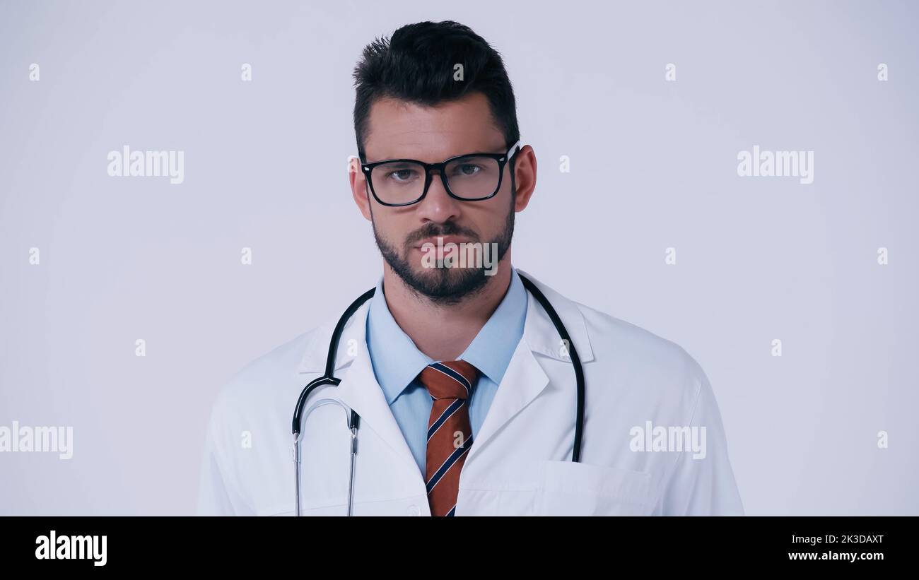médecin barbu dans les lunettes et avec stéthoscope regardant la caméra isolée sur gris, image de stock Banque D'Images