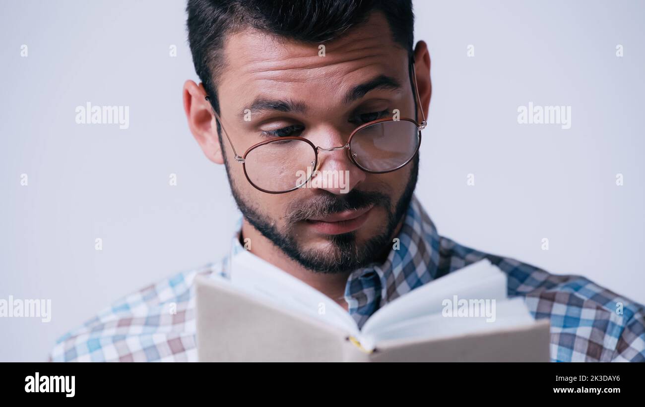pensive nerd étudiant dans le livre de lecture de lunettes isolé sur gris, image de stock Banque D'Images