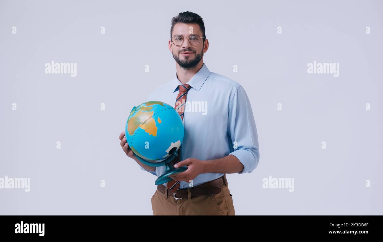 professeur souriant en chemise et lunettes tenant le globe isolé sur gris, image de stock Banque D'Images