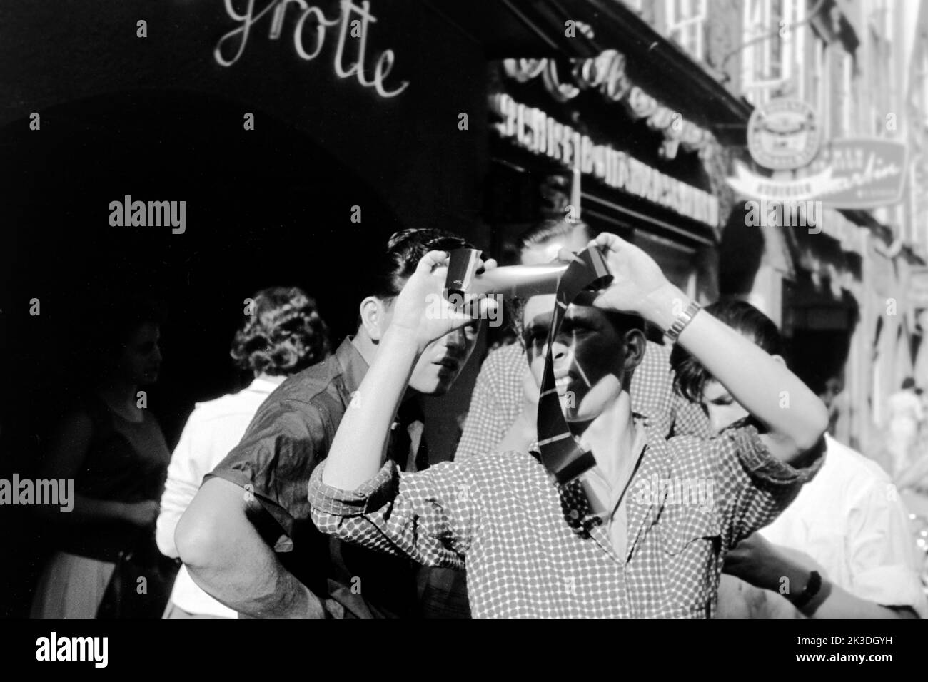 Junge Männer betrachten einen Negativfilm im Gegenlicht, Salzbourg, vers 1960. Jeunes hommes regardant un film négatif en contre-jour, Salzbourg, vers 1960. Banque D'Images