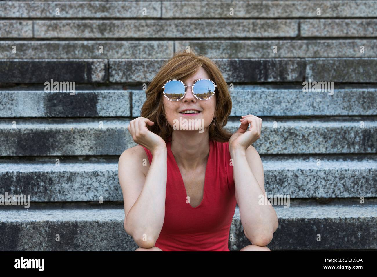 Jeune femme européenne avec des lunettes de soleil reflétant le paysage autour d'elle Banque D'Images