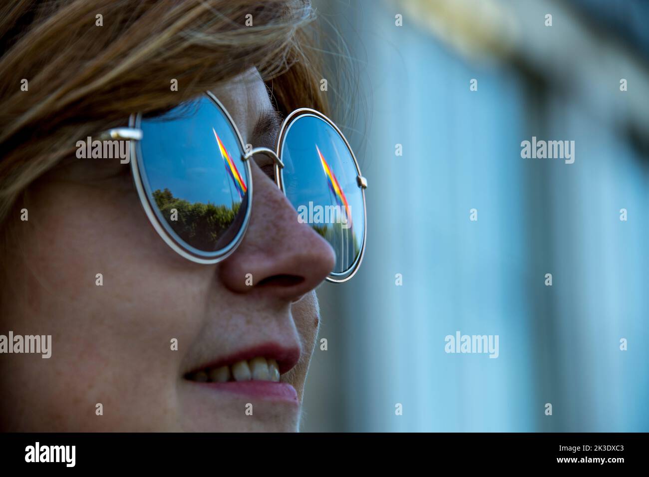 Jeune femme européenne avec des lunettes de soleil reflétant certains drapeaux arc-en-ciel Banque D'Images