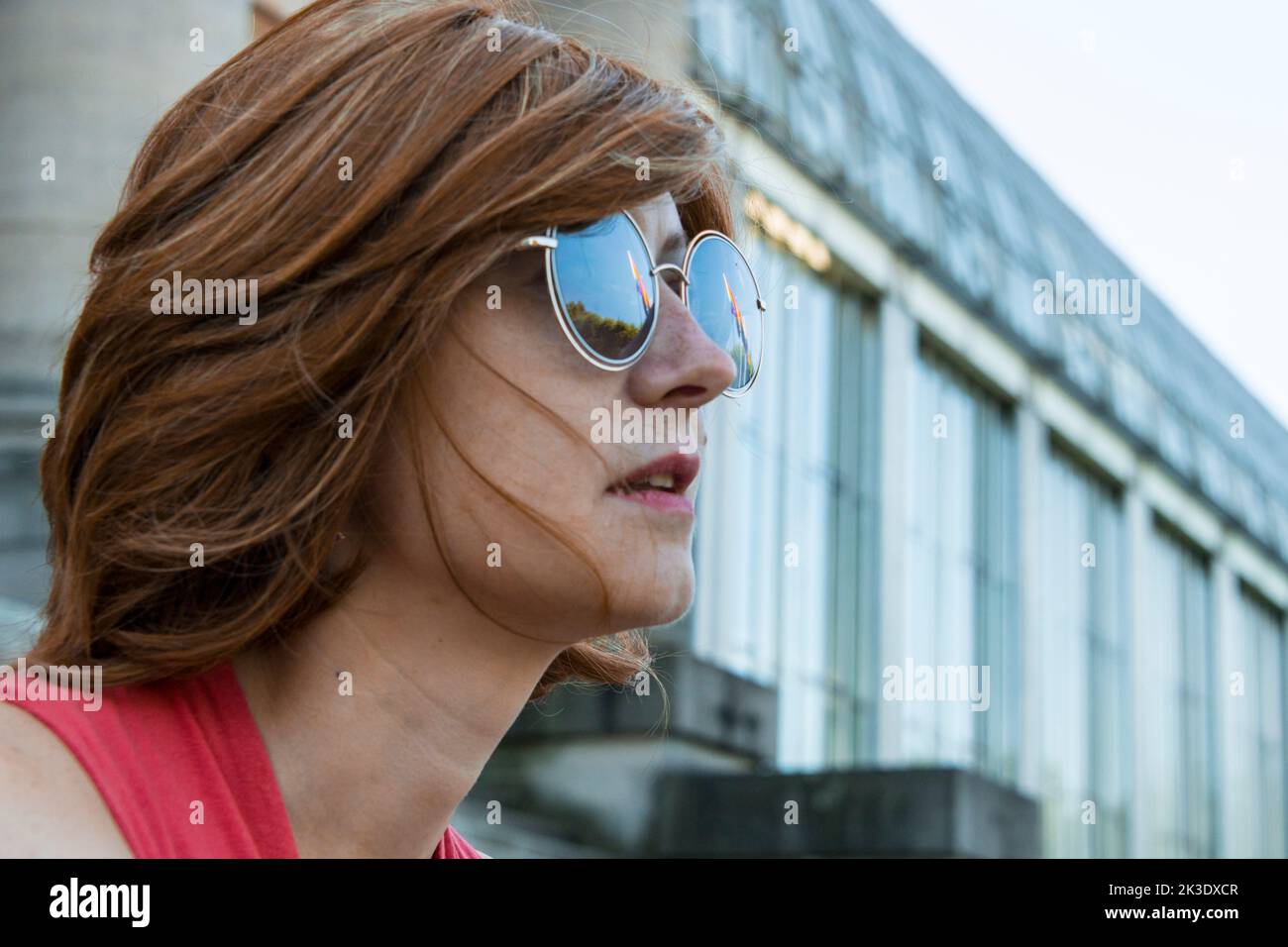 Jeune femme européenne avec des lunettes de soleil reflétant certains drapeaux arc-en-ciel Banque D'Images