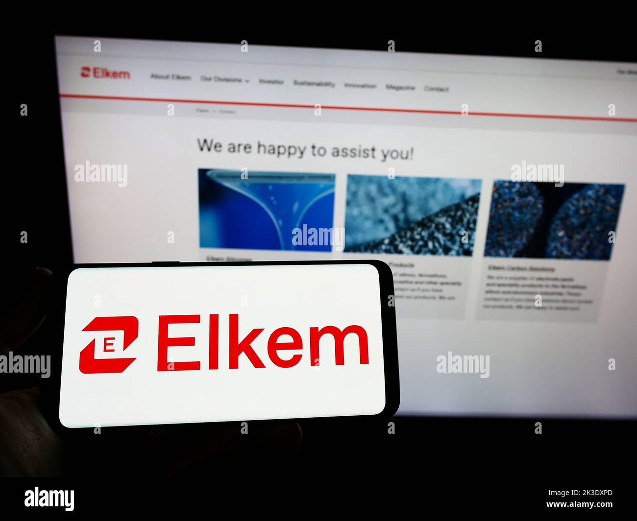 Personne tenant un smartphone avec le logo de la société norvégienne silicones Elkem ASA sur l'écran devant le site. Mise au point sur l'affichage du téléphone. Banque D'Images
