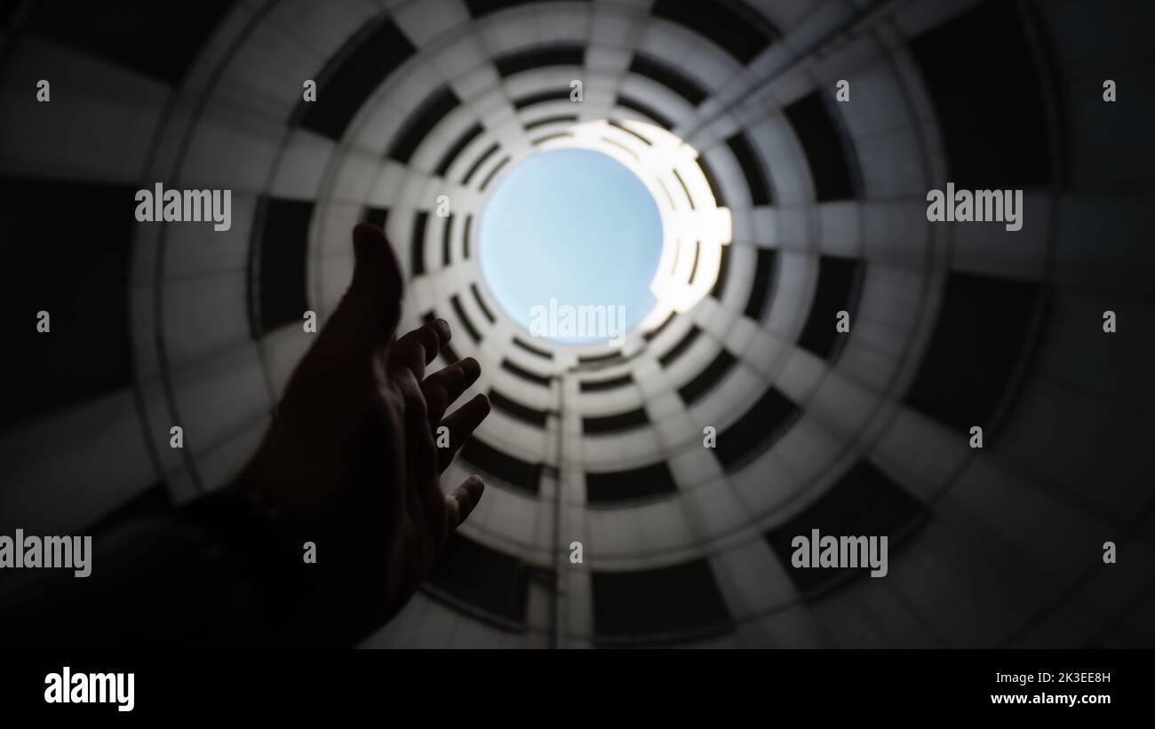Tube d'entrée en spirale d'un garage de stationnement en béton avec vue sur le ciel bleu et les nuages blancs. Prise de vue grand angle de bas en haut Banque D'Images