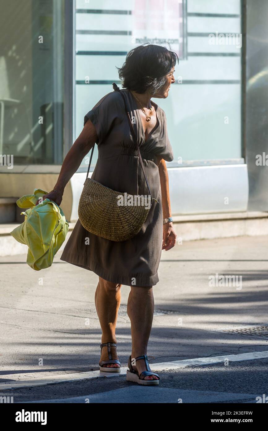 Femme française mature qui franchit le trottoir pour traverser la route - Chatellerault, Vienne (86), France. Banque D'Images