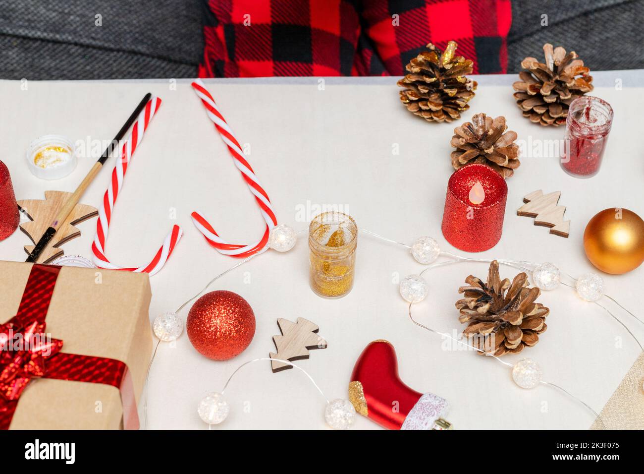 Activités artisanales de Noël pour les enfants à la maison. Un petit enfant peint des cônes de pin et des décorations d'arbre de Noël en bois à la maison. Concept bricolage vacances pour enfant Banque D'Images