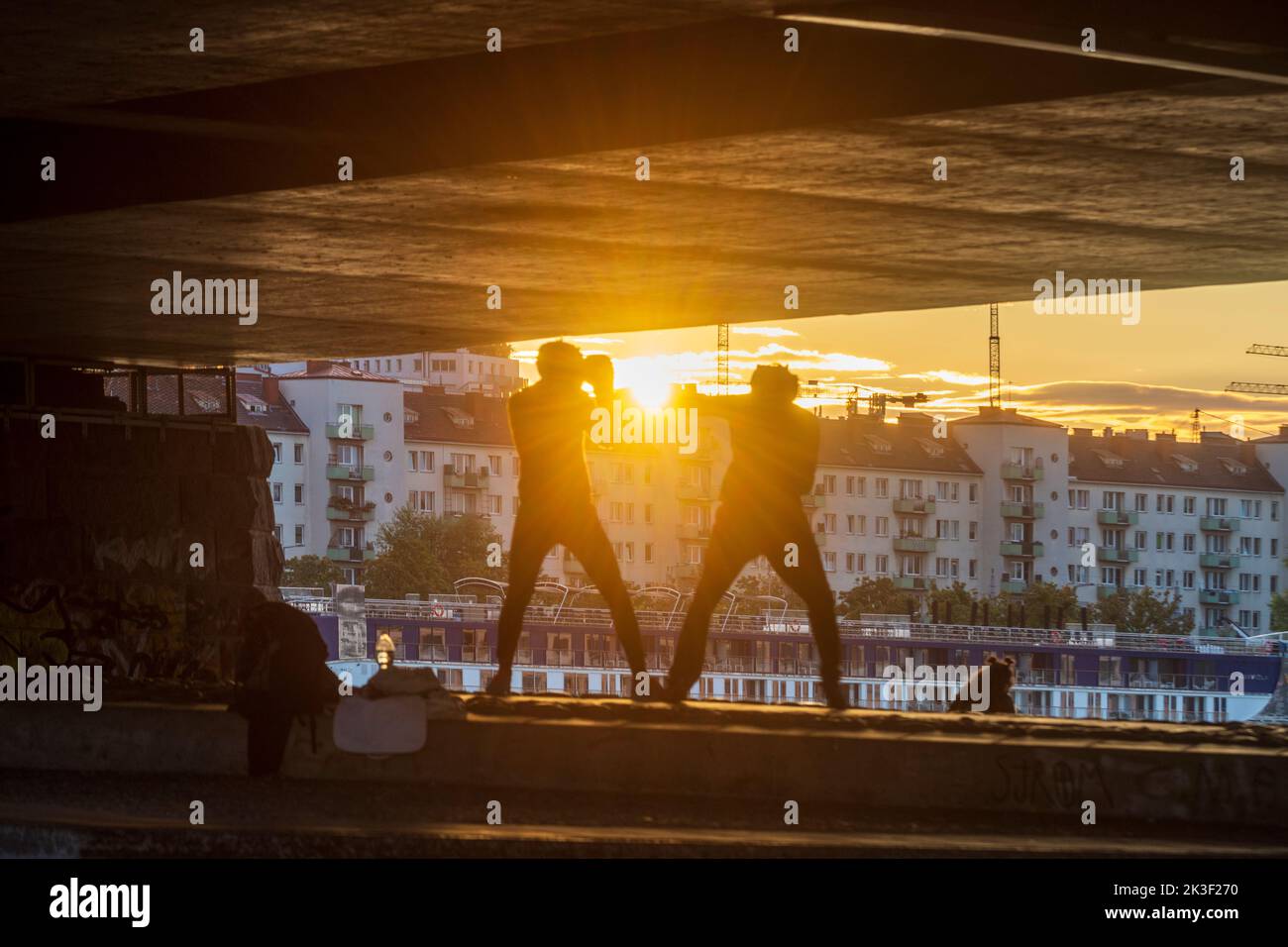 Wien, Vienne: 2 hommes sport de boxe sous le pont Reichsbrücke, coucher de soleil, bateau de croisière en 22. Donaustadt, Wien, Autriche Banque D'Images