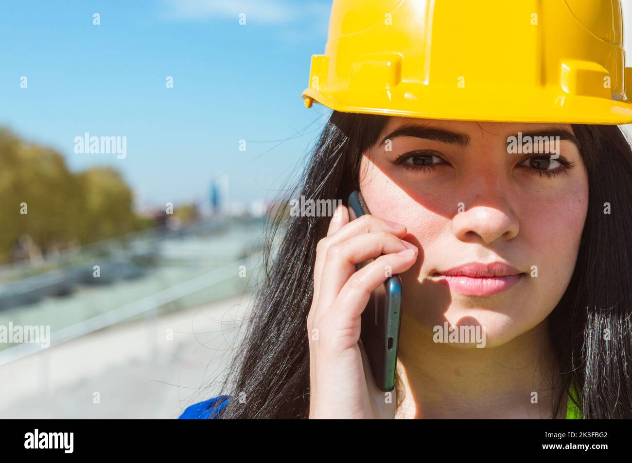 gros plan de la femme vénézuélienne du caucase du sud, avec un casque jaune, reçoit des instructions de son patron par téléphone, copie spac Banque D'Images