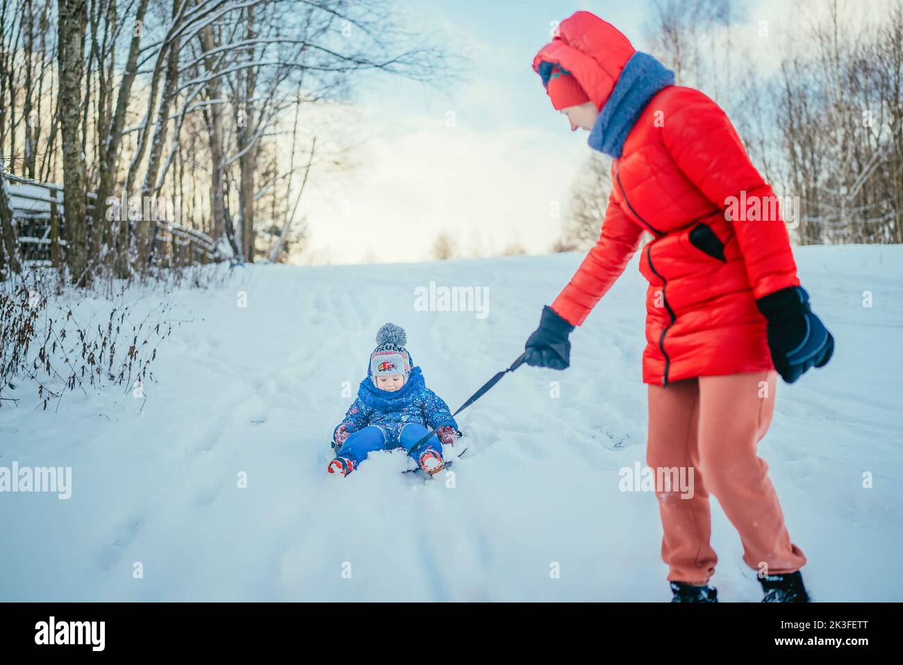 maman et petit fils dans une veste bleue dans une forêt enneigée en tubing par temps froid. Banque D'Images