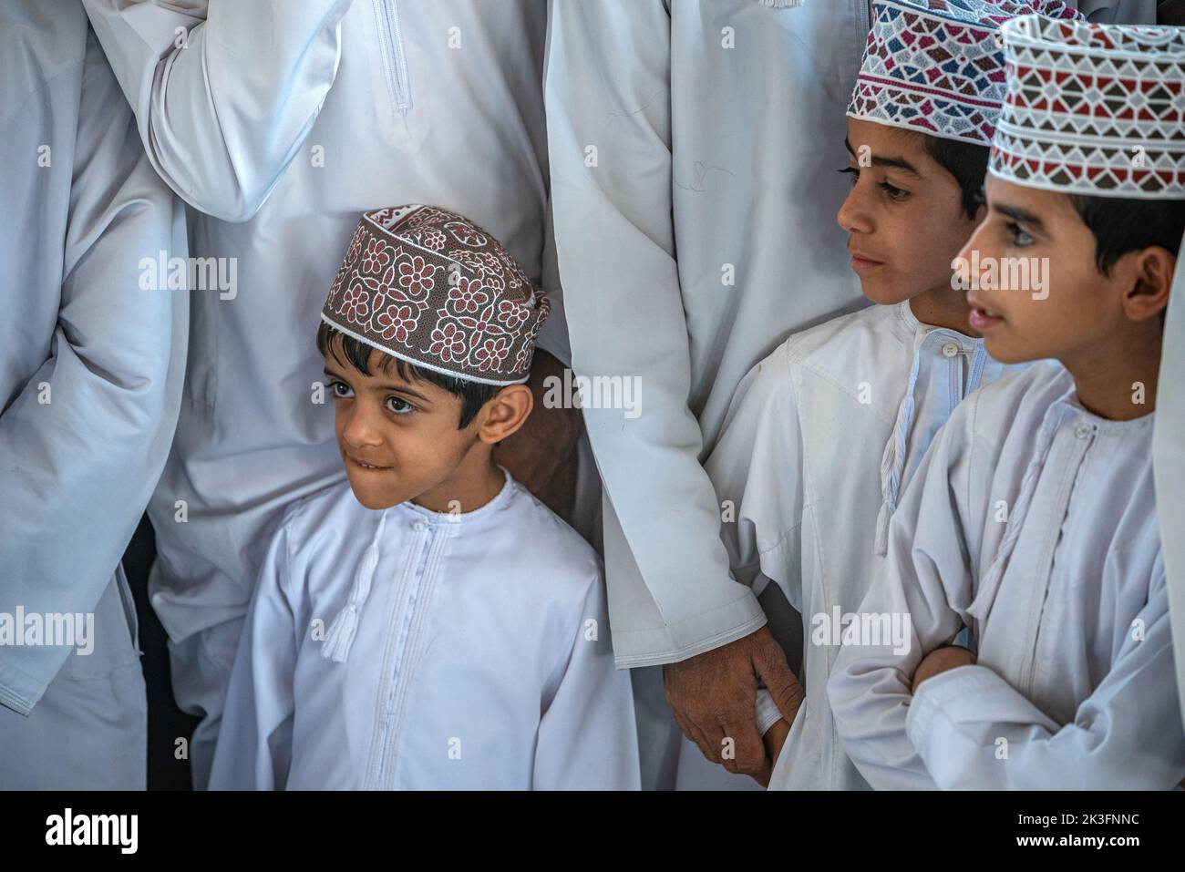 Trois jeunes garçons avec kuma (chapeau rond traditionnel omanais) au marché du bétail du vendredi matin, Nizwa, Oman Banque D'Images