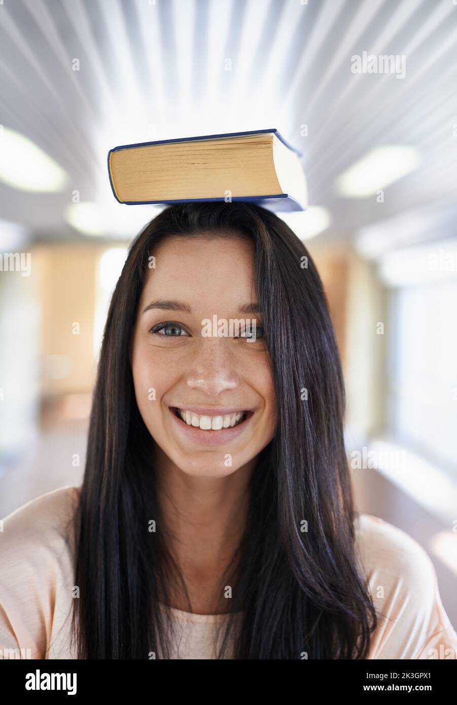 Shes est enthousiaste à l'idée d'apprendre. Portrait d'une jeune étudiante attrayante en équilibrant un livre sur sa tête. Banque D'Images