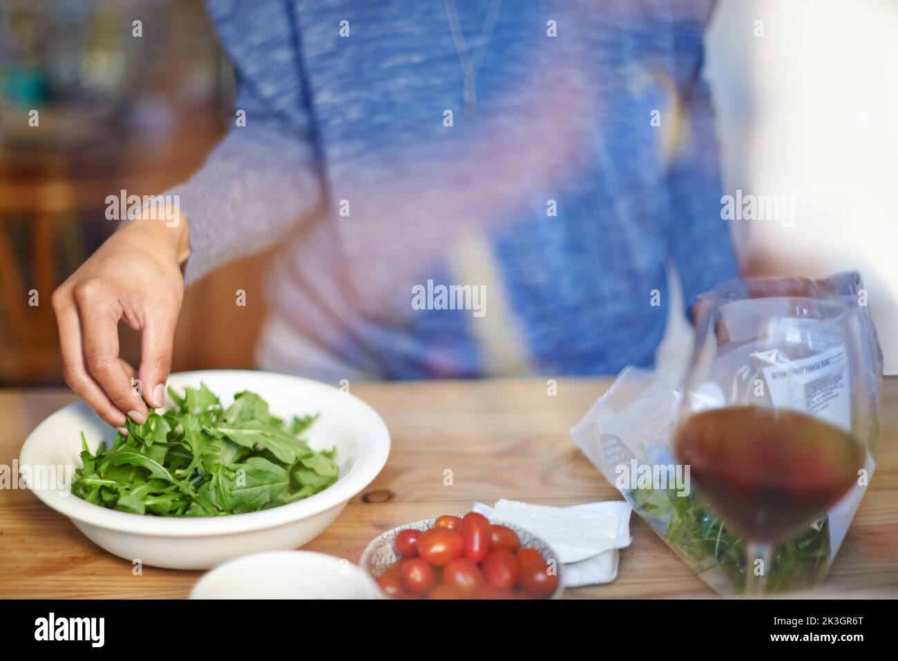 Faire un déjeuner sain. Une jeune femme qui fait une salade dans sa cuisine. Banque D'Images