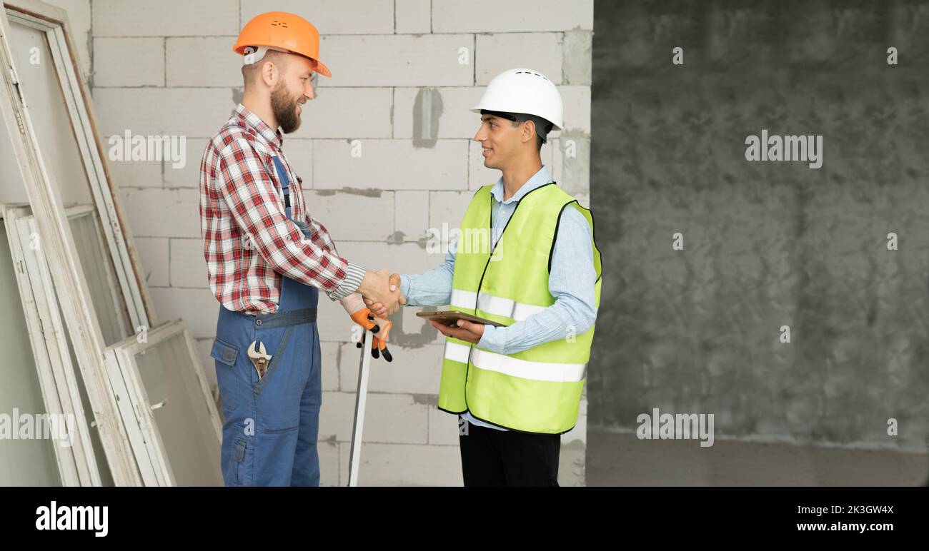 L'entrepreneur et l'ingénieur se sont fait serrer la main pour accepter de construire une maison ou un bâtiment. Le travailleur de la construction accepte les conditions de salaire d'emploi. Le client entre la main Banque D'Images