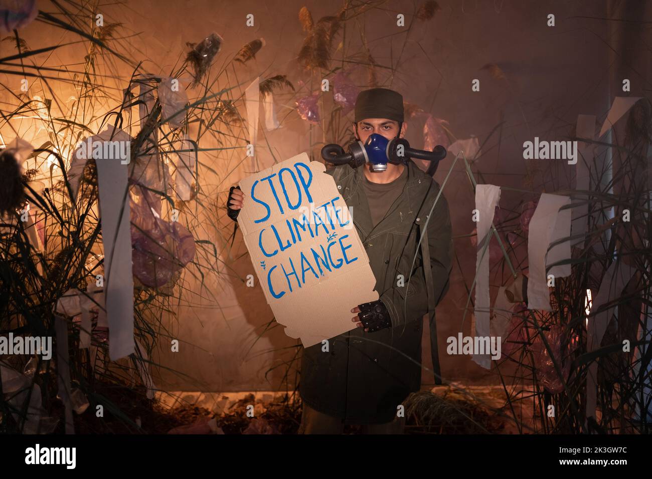 Protection de l'environnement. Un homme dans un masque à gaz tient une affiche avec le mot STOP changement climatique dans la fumée. Protection de l'environnement. Pollution de l'air. Nocif Banque D'Images