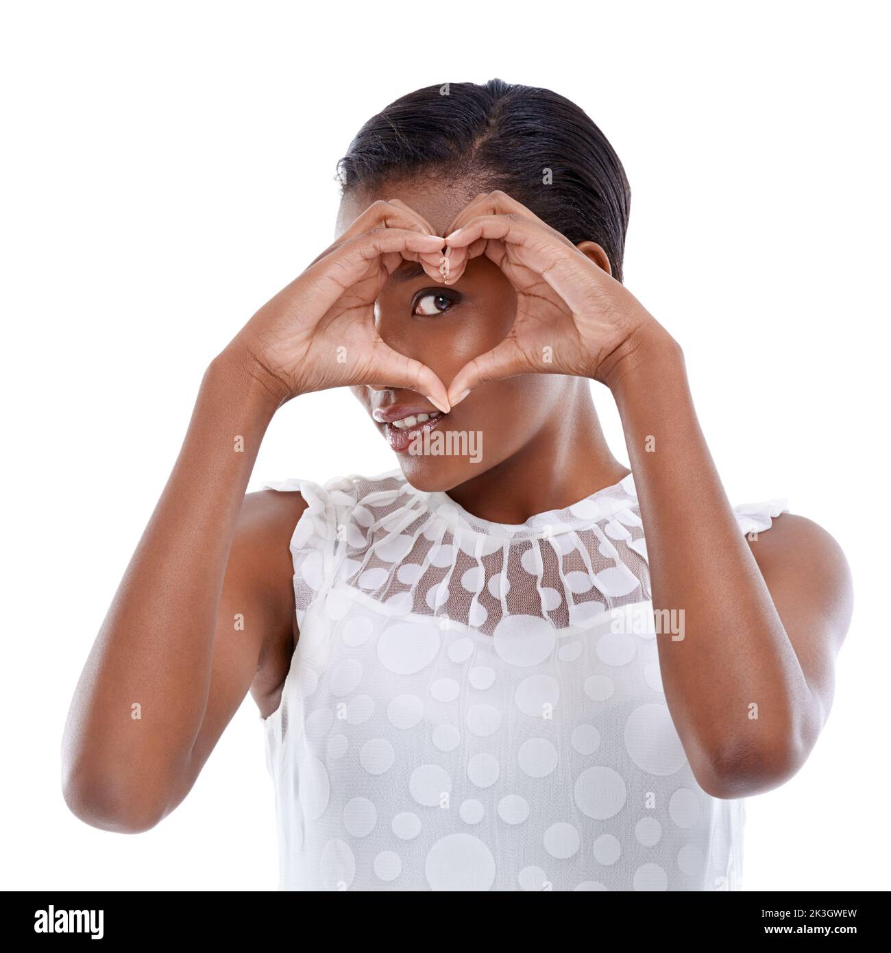 Je crois en une chose appelée l'amour. Une jeune femme faisant un geste de coeur contre un fond blanc. Banque D'Images
