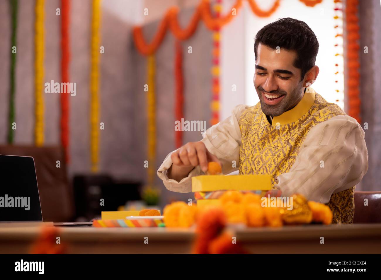 Jeune homme mangeant des ladoos au bureau pendant la fête de Diwali Banque D'Images