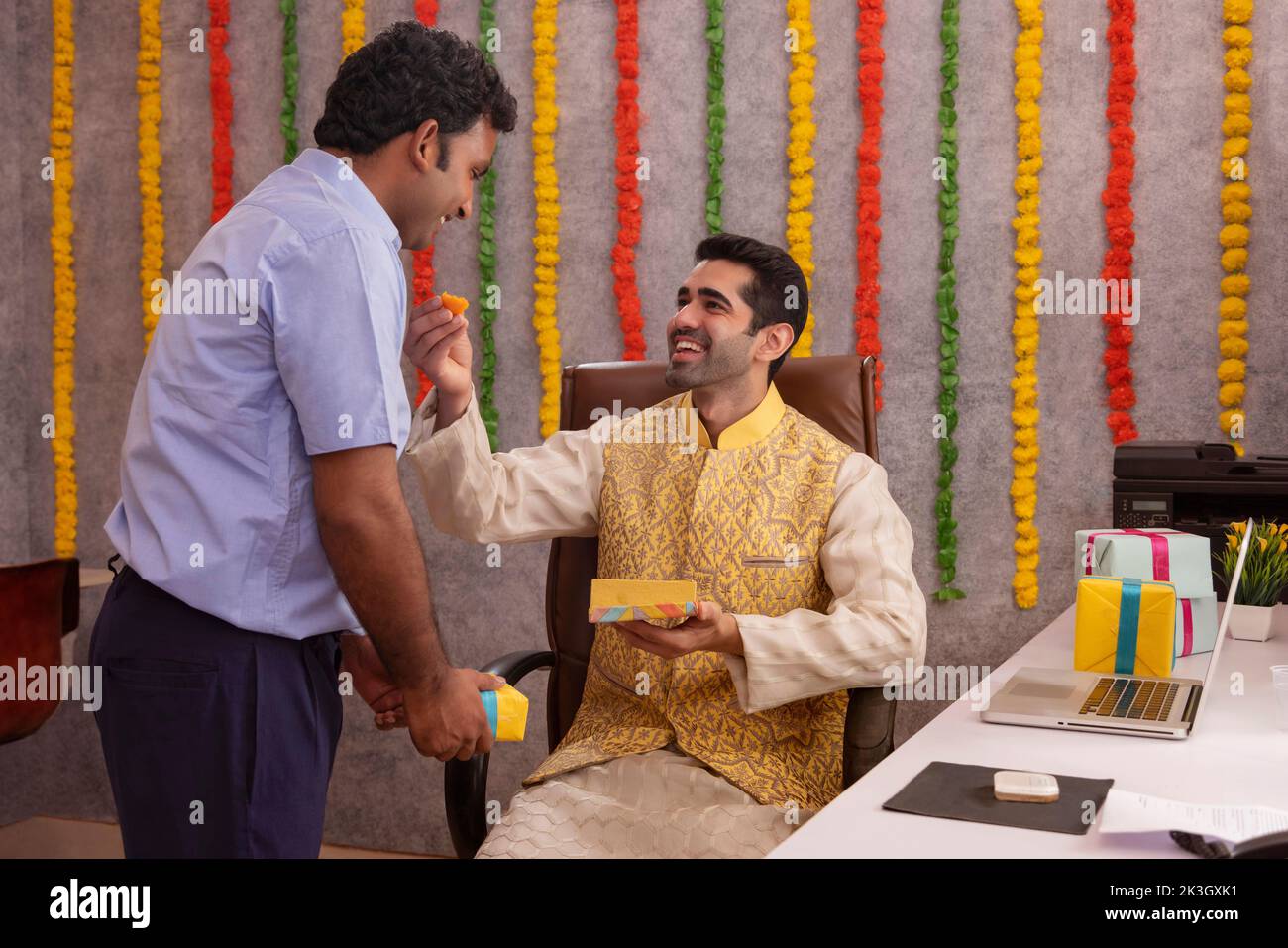 Employé nourrissant des ladoos à son collègue pendant la fête de Diwali Banque D'Images