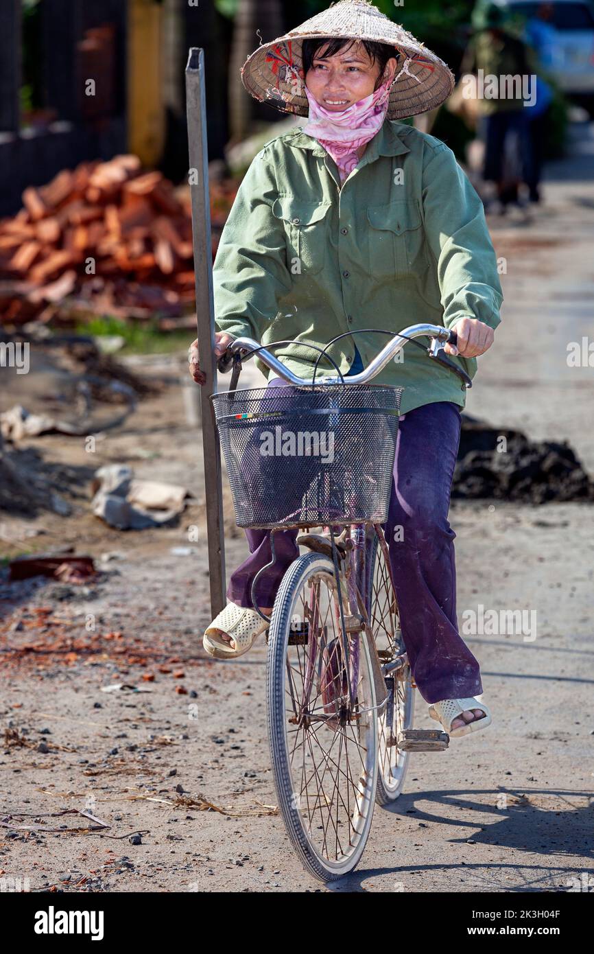 Cycliste portant un chapeau de bambou sur la route de campagne, Hai Phong rural, Vietnam Banque D'Images