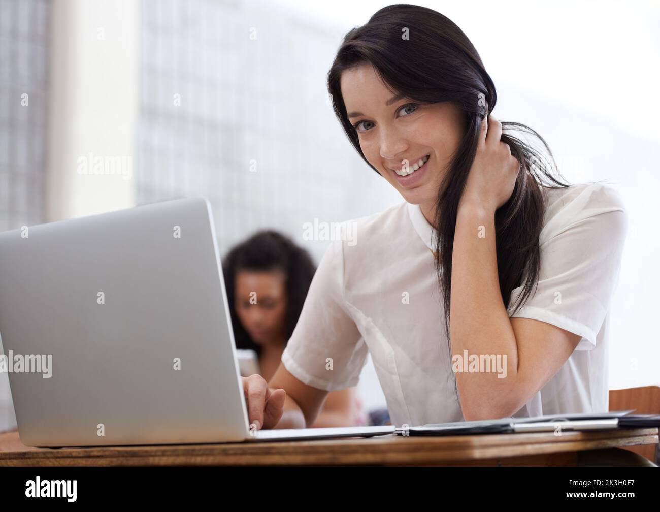 Obtenir les notes qu'elle veut. Un jeune étudiant heureux travaillant à un ordinateur portable en classe. Banque D'Images