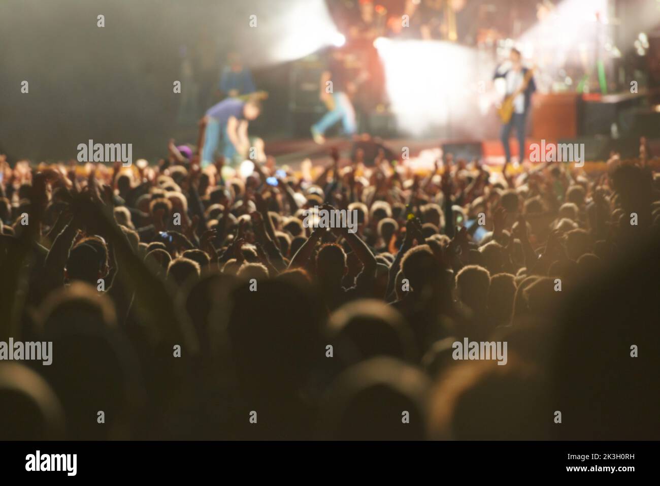 Tous les yeux fixés sur la scène. Vue arrière d'un public plein de regarder un grand acte musical avec leurs mains levées. Banque D'Images