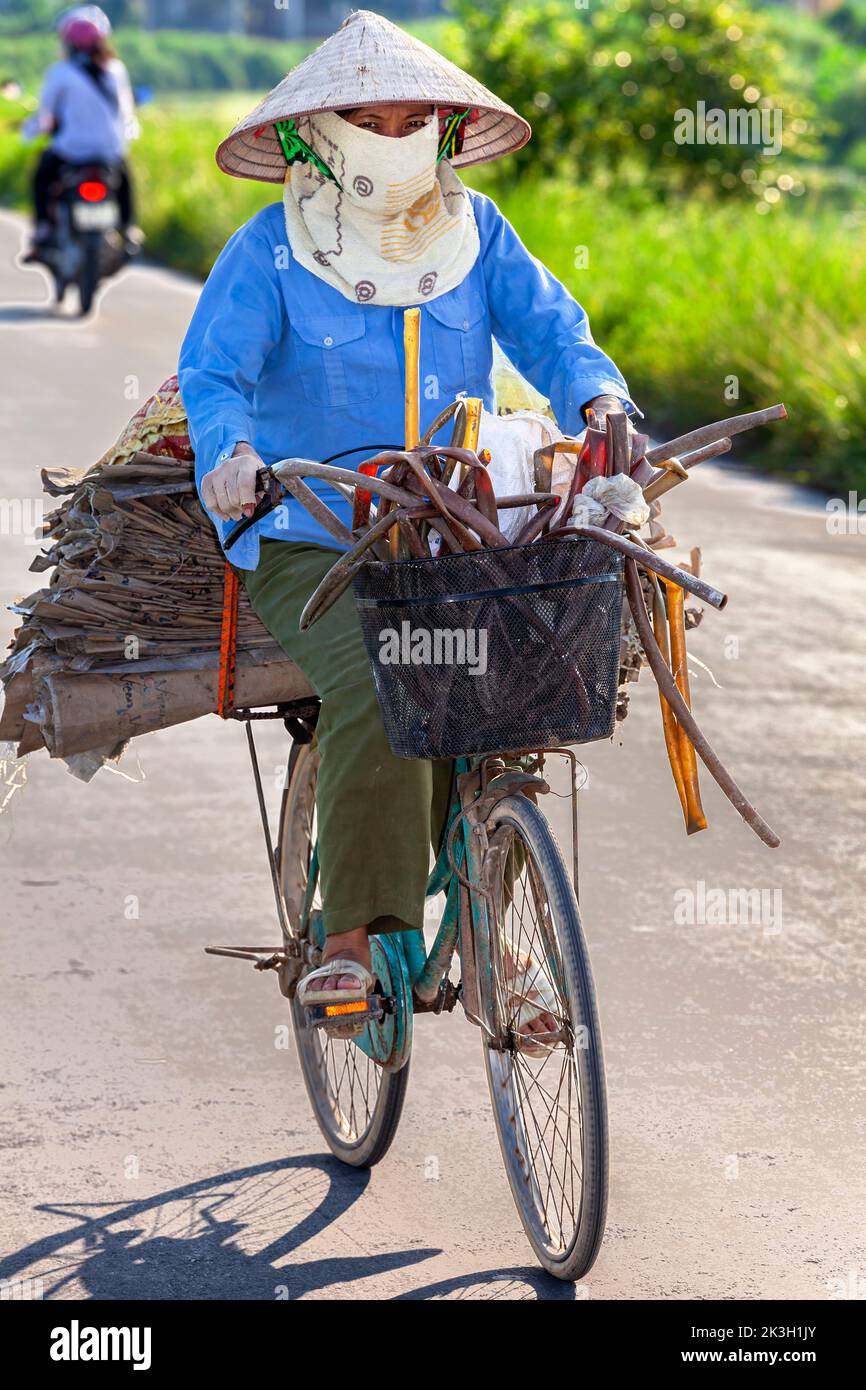 Cycliste portant un chapeau de bambou sur la route de campagne, Hai Phong rural, Vietnam Banque D'Images