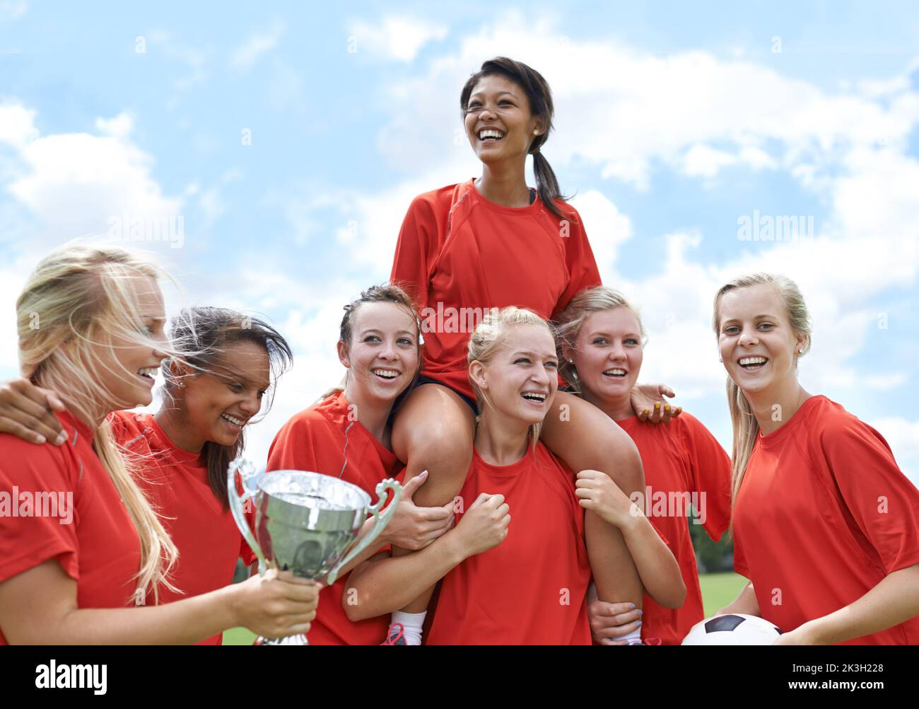 Une autre tasse dans l'armoire à trophées. Portrait d'une équipe de football entièrement féminine qui élève son capitaine en triomphe. Banque D'Images