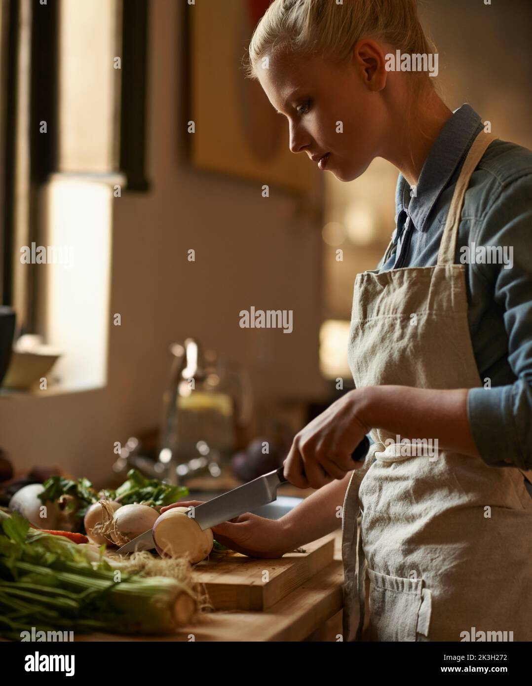 Shes a une passion pour la bonne cuisine. Une belle jeune femme préparant un repas dans sa cuisine. Banque D'Images