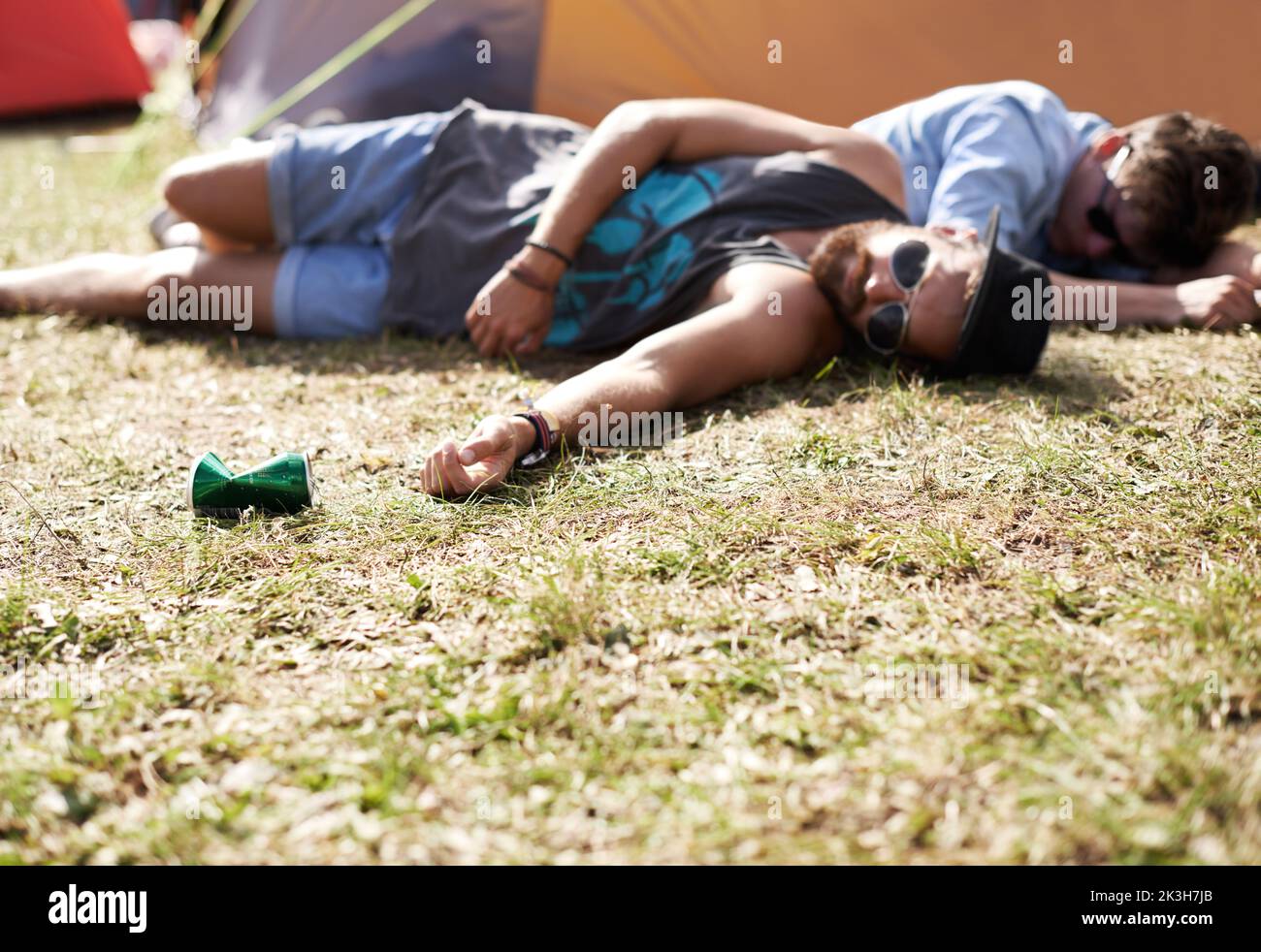 Je ne suis pas tombé le sol avait juste besoin d'un câlin. Deux jeunes hommes qui s'étaient couché sur l'herbe après avoir trop bu lors d'un festival en plein air. Banque D'Images