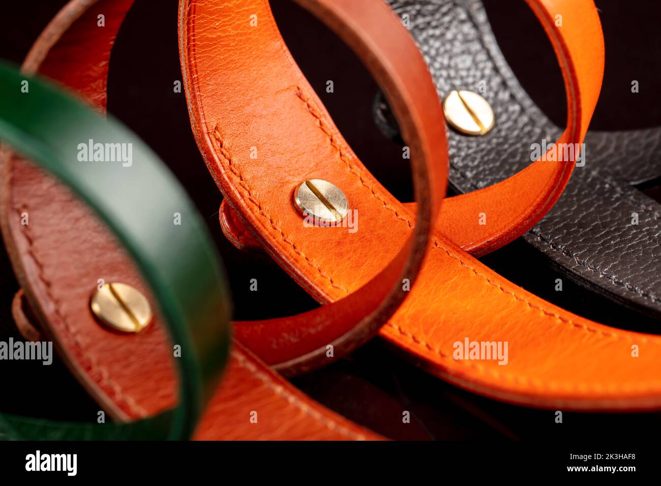 Un groupe de ceintures en cuir multicolores sur fond noir. Banque D'Images