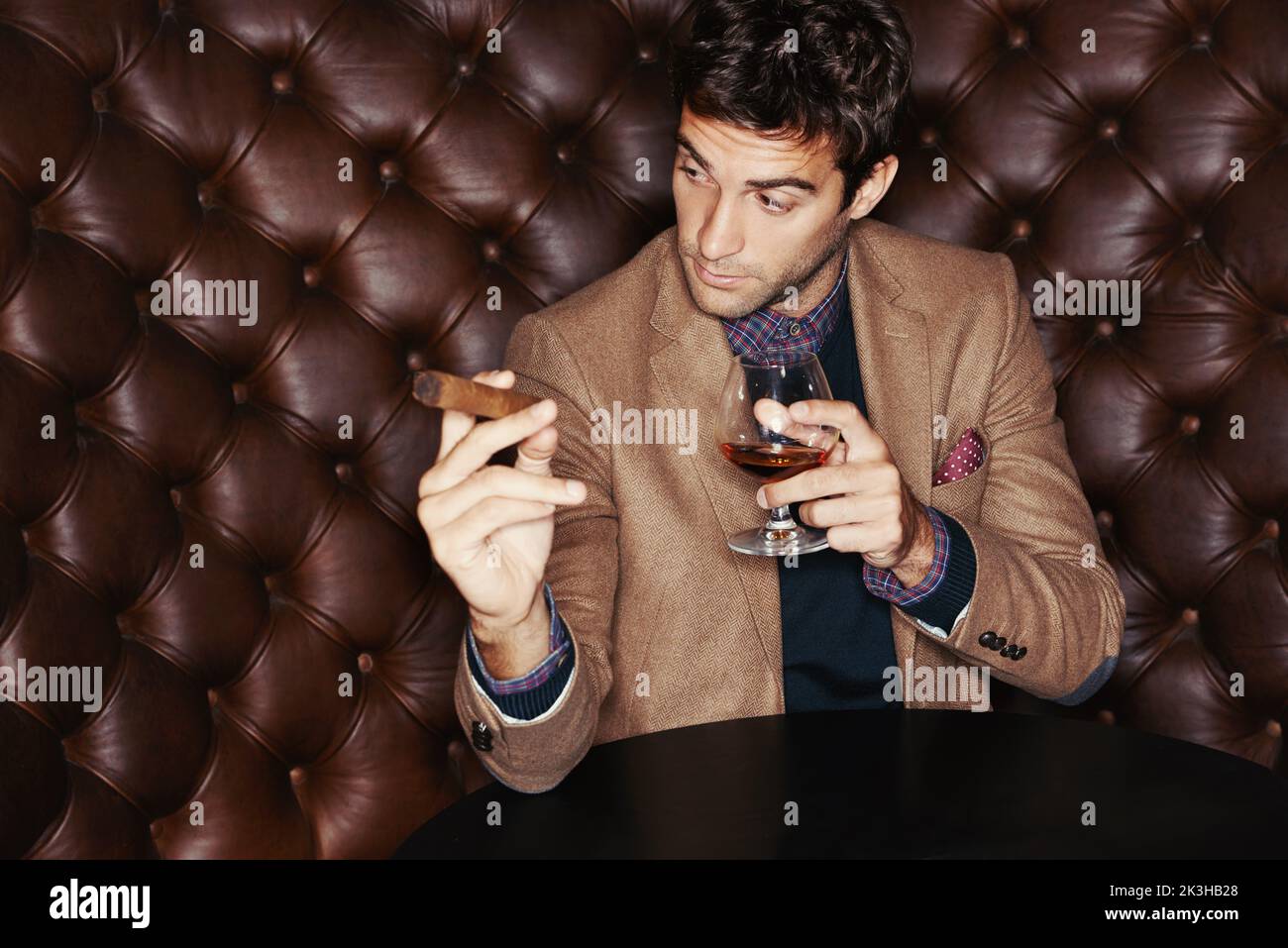 Ils vont parfaitement ensemble. Un homme élégant qui boit du whisky et fume un cigare. Banque D'Images