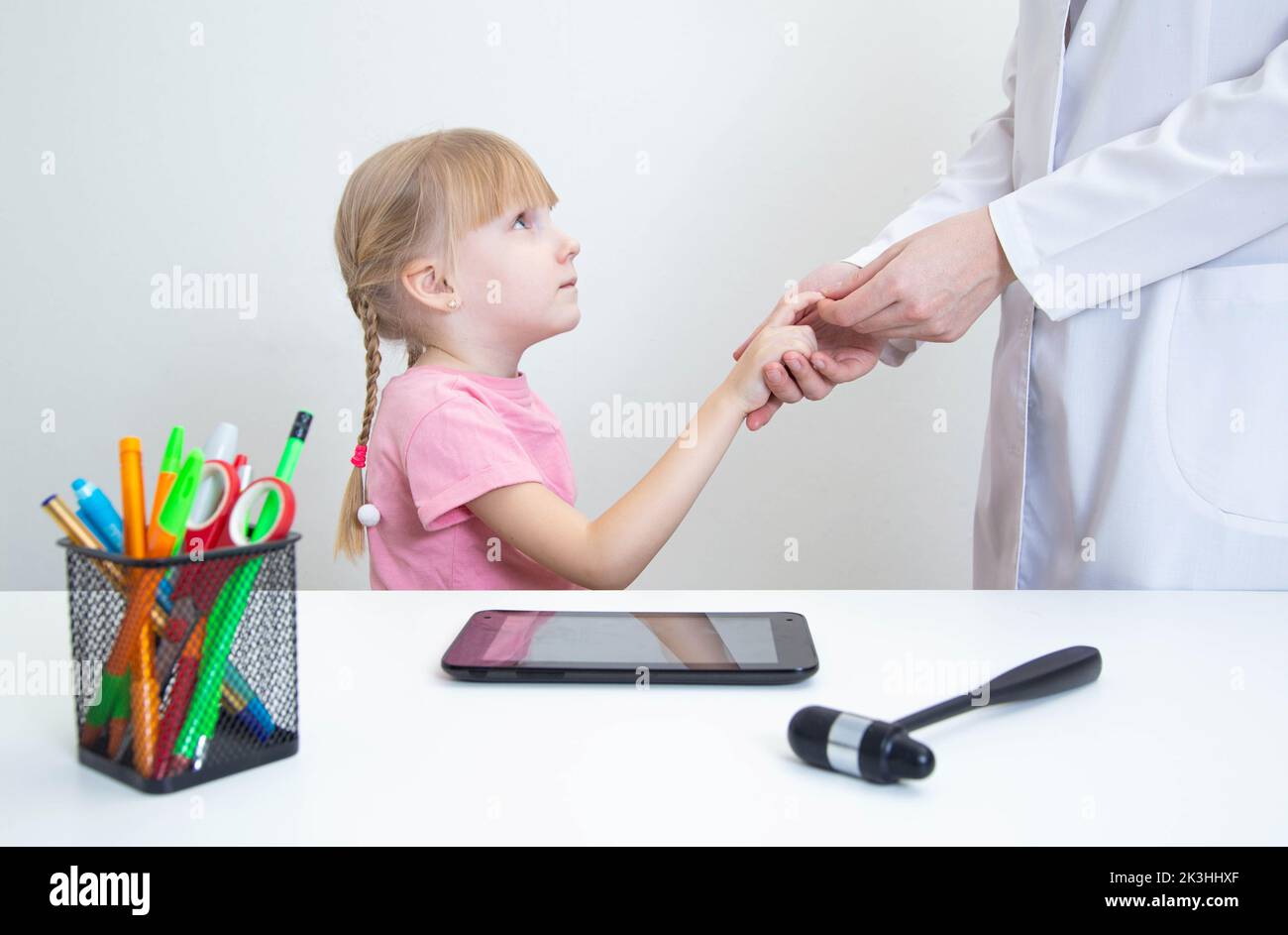 Un médecin neurologue vérifie le réflexe pathologique d'un hoffman chez une fille pour détecter la présence de neuropathologies. Système nerveux, neurologie Banque D'Images