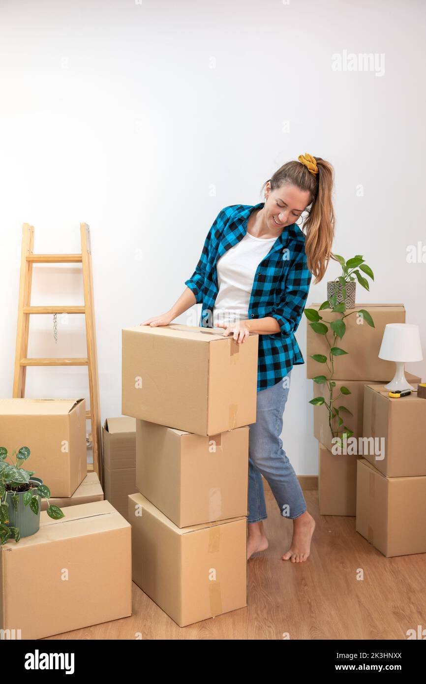 Jeune femme attrayante heureux emballage boîtes en carton se déplaçant dans une nouvelle maison. Nouvelles clés de maison, nouvelle vie. Immobilier. Banque D'Images