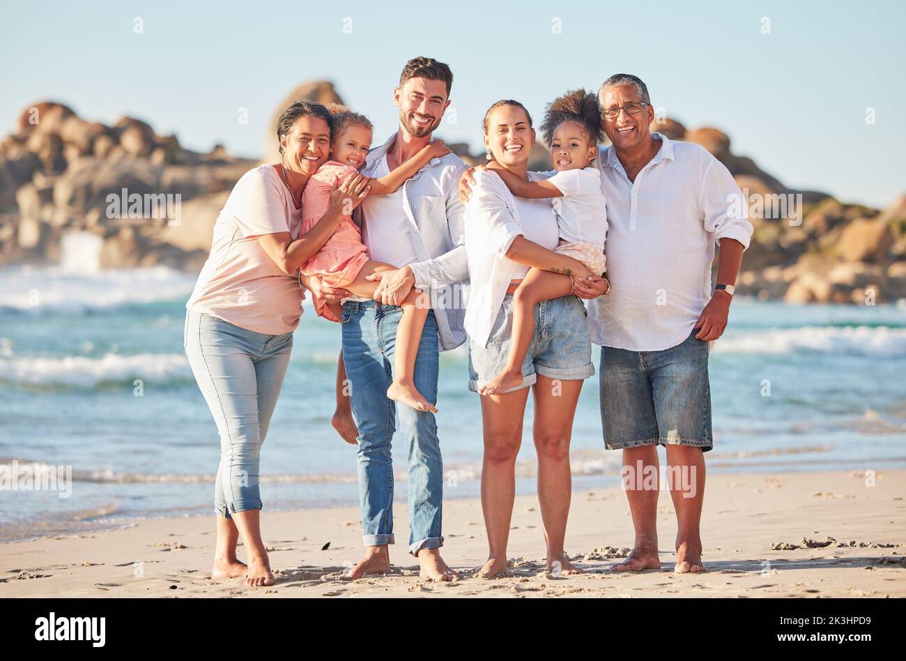 Des vacances d'été en famille, en portrait et à la plage, avec des gens heureux qui se greffent sur l'océan. Liberté, amour et voyage en mer avec la famille interraciale hug Banque D'Images