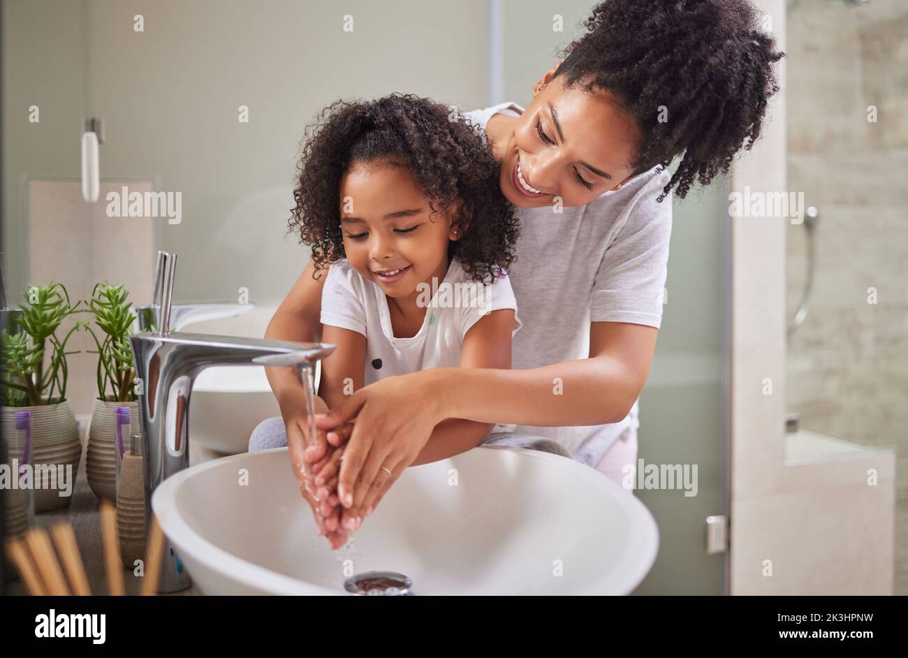 Famille, se laver les mains et l'enfant avec la maman rinçage, le nettoyage et une bonne hygiène contre les bactéries ou les germes pour la protection contre les infections ou les virus dans la salle de bains Banque D'Images