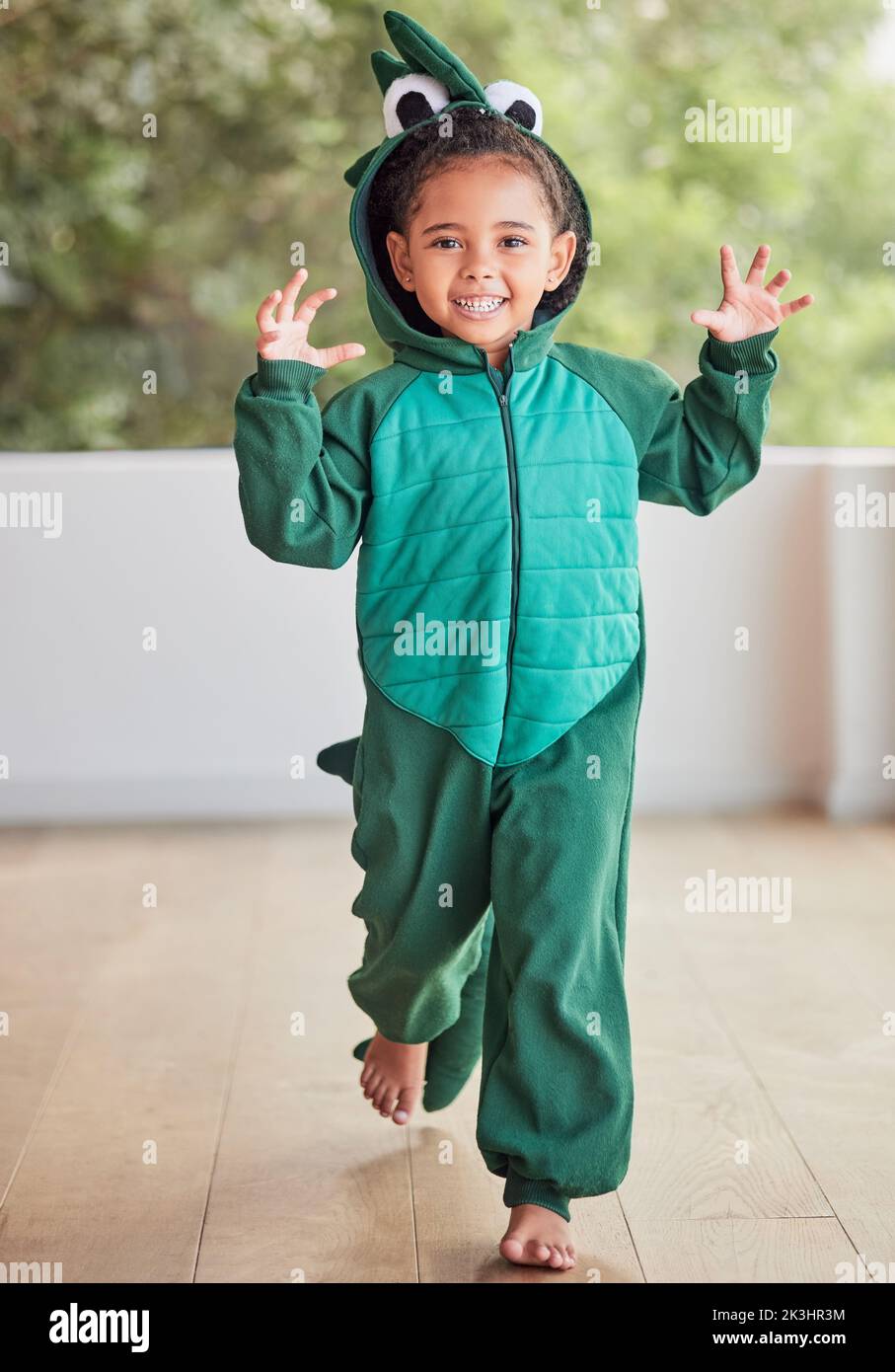 Costume créatif, enfant et halloween par fille courir dans un costume de crocodile, jouer et rire à la maison. Fantaisie, heureux et visage d'un enfant excité à Banque D'Images