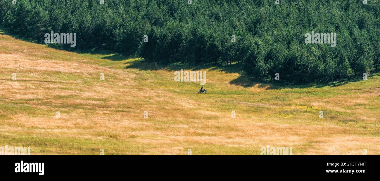 Homme en vélo de terre moto de croix à travers Zlatibor paysage herbeux le jour ensoleillé d'été, foyer sélectif Banque D'Images