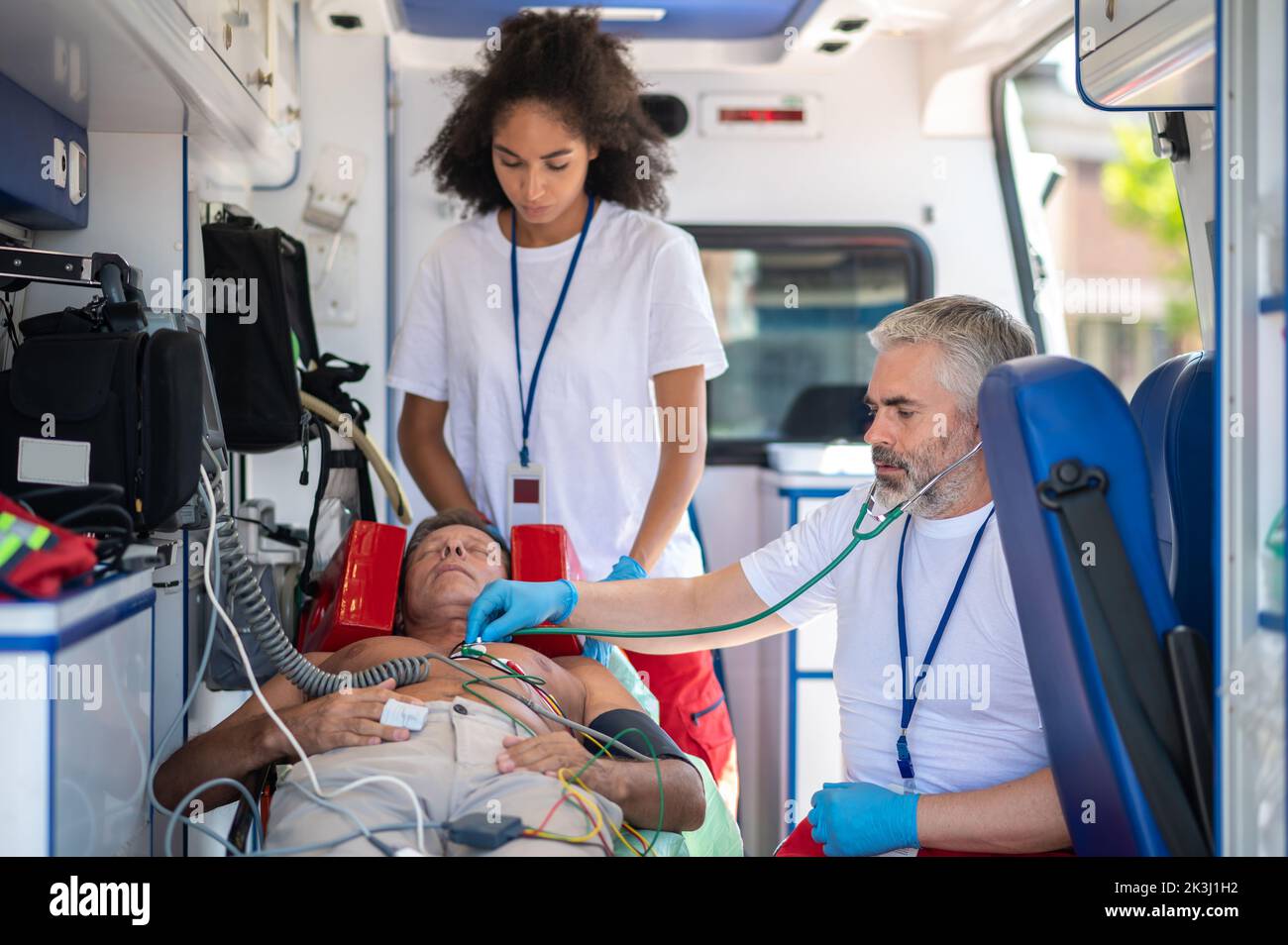 Ambulanciers paramédicaux examinant l'homme inconscient dans le véhicule d'urgence médical Banque D'Images