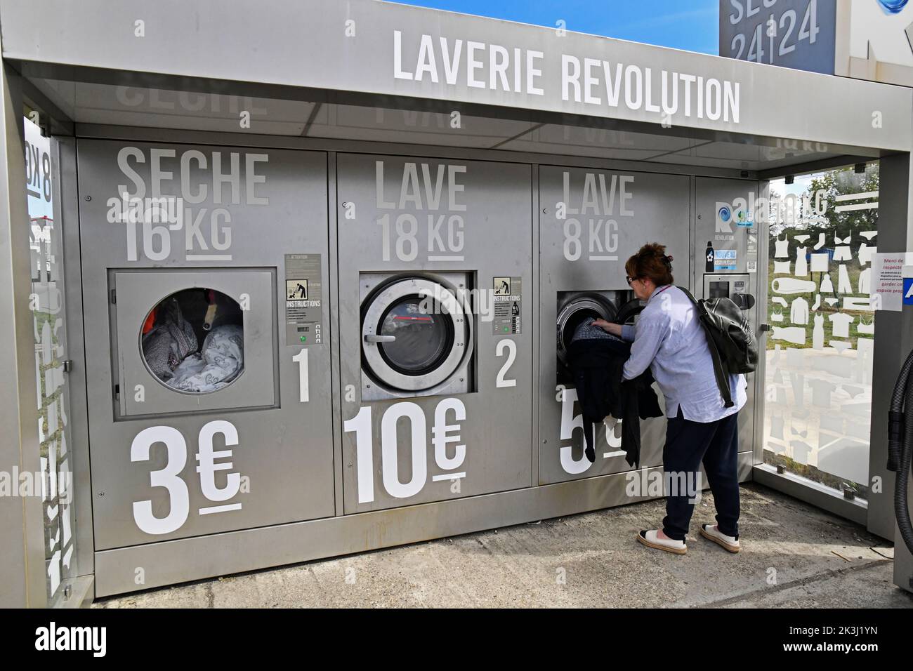 Femme utilisant une laverie externe appelée Laverie Revolution en France Banque D'Images