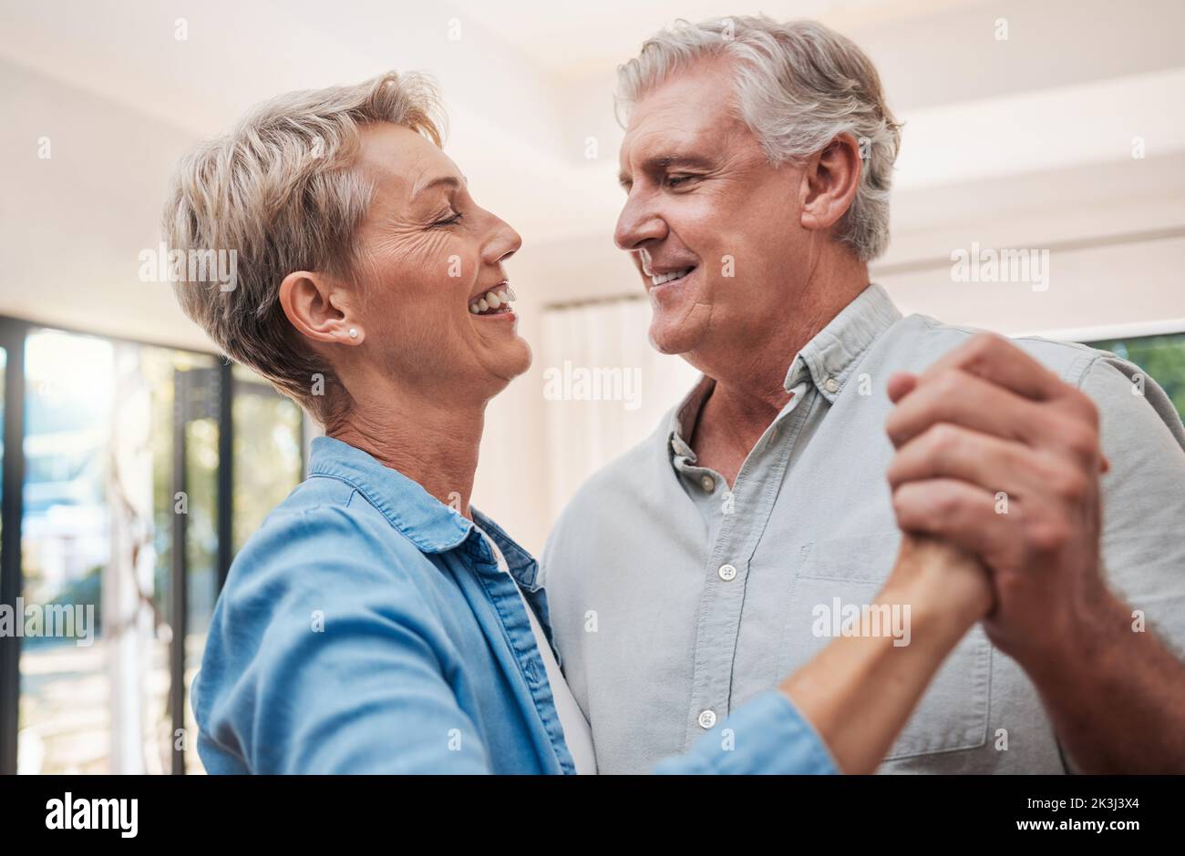Couple âgé, heureux et dansant dans le salon, profitant de la retraite. Portrait de l'homme et de la femme âgés qui dansent ensemble dans leur maison, souriant Banque D'Images
