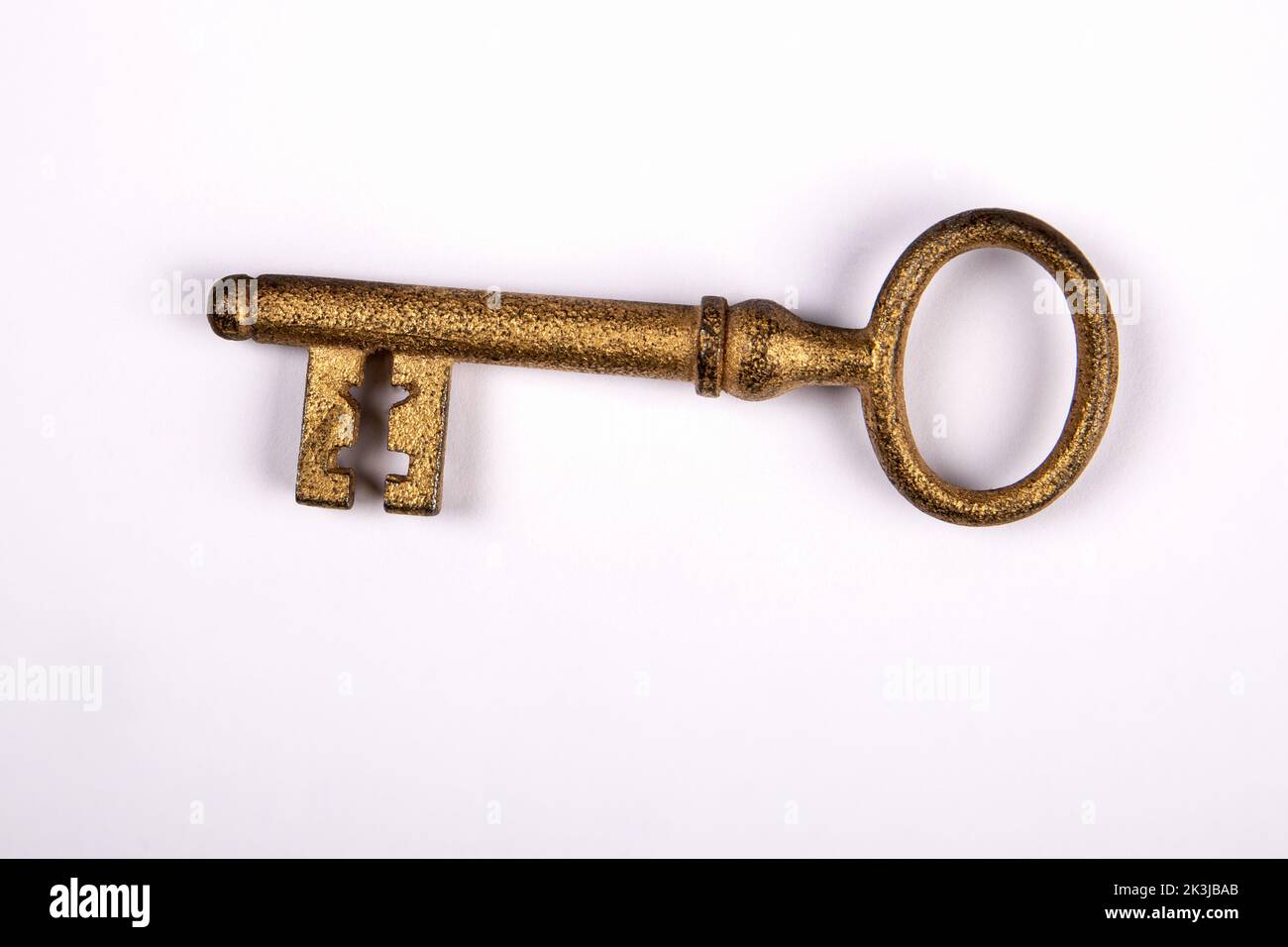 Ancienne clé de porte dorée sur fond blanc. Banque D'Images