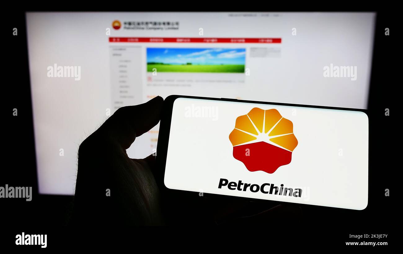 Personne tenant un téléphone portable avec le logo du pétrole et du gaz chinois PetroChina Company Limited à l'écran en face de la page Web. Mise au point sur l'affichage du téléphone. Banque D'Images